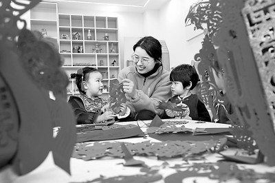 1月12日，河北省邢台市平乡县某幼儿园的老师和小朋友一起剪窗花。新华社发